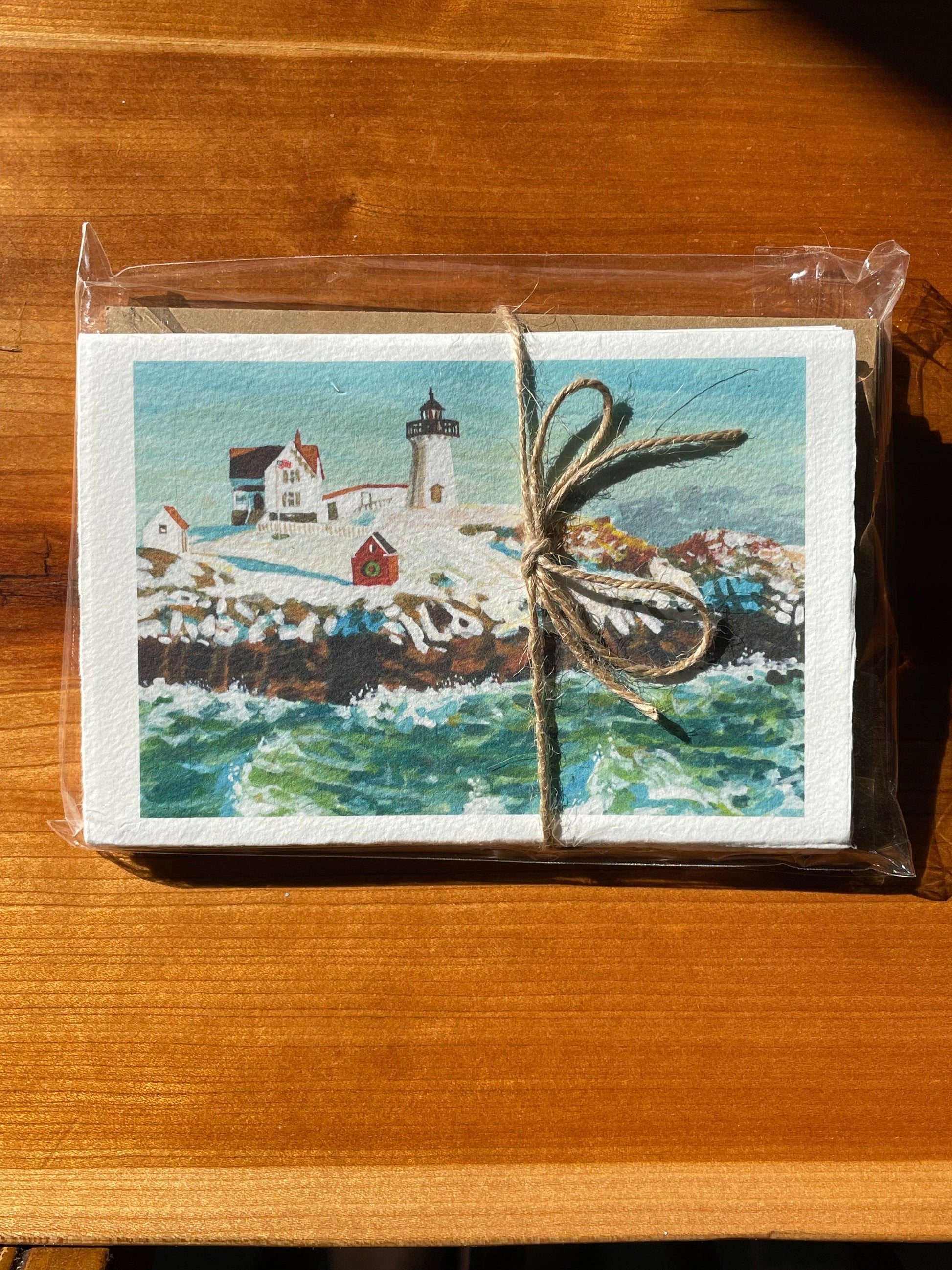 Print of handpainted nubble lighthouse by Brandy Cressey for Florence Farmstead. Nubble Lighthouse in York, Maine in the winter with Christmas wreath and crashing waves.